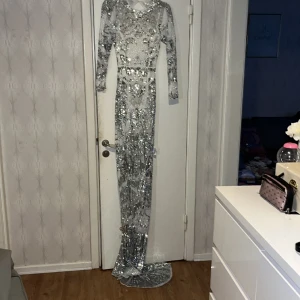 Förlovningsklänning/brudklänning mermaid stil från asos slutsåld  - Endast använd en gång och kemtvättad och absolut nyskick alltid varit skyddad i textilskydd, även en utmärkt nyårsklänning om du vill vara snyggast på feste, öppen rygg. Silver/glittrig !
