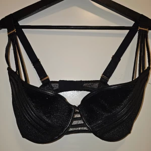 BH Honey Birdette 70E - Beskrivning: Svart BH i sammet med fejkläder-detaljer. Märke: Honey Birdette Storlek: 70E (70D kan nog också ha den) Skick: Gott skick Material:   Nakenkatt finns i hemmet