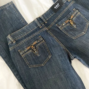 Lågmidjade jeans  - Coola lågmidjade jeans med detaljer på bakfickorna! Midjemåttet rakt över är ca 42cm och innerbenslängden 84cm💓