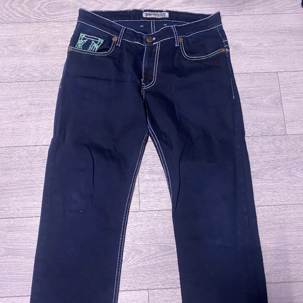 (INTE ÄKTA) säljer ett par mörkblåa med neongrön tjock stygn true religion baggy byxor. Nypris vet ej. . Jeans & Byxor.