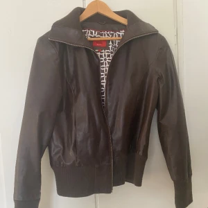 Skinnjacka - Snygg skinnjacka! Köpt second hand, i fint skick förutom några små tecken på slitage enligt bild, men inget som märks mycket i verkligheten. OBS: Kommer vara bortrest en del under sommaren så är inte alltid tillgänglig att posta/skicka fler bilder di