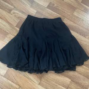 Svart kjol med volanger nertill från nakd i storlek 32, stretchig i midjan, aldrig använd 