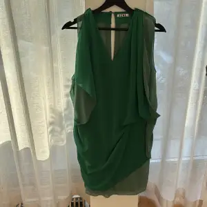 Kort Acne klänning, öppen i rygg.  Färg, stark grönt med kontrast draperande detaljer i ljusare grönt.  Stl 38. Sparsamt använd.  