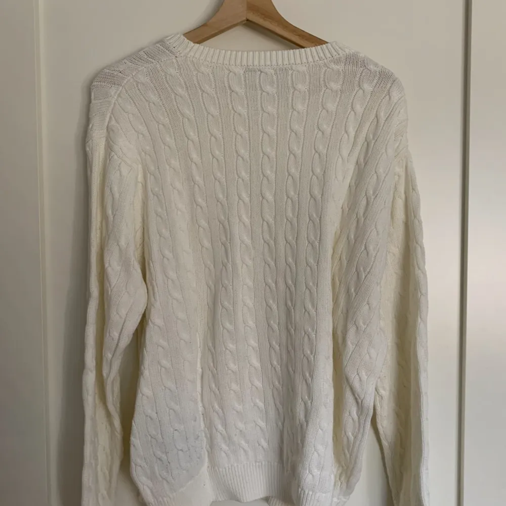 Mysig, avslappnad tjock kabelstickad drop shoulder-tröja i vit från Brandy Melville. Den är i bra skick, endast använd 3-4 gånger och är one size.  Ursprungligt pris: 38$ (US-dollar) Obs: köparen står för frakten!. Tröjor & Koftor.