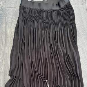 Säljer denna fina svarta kjol i plisserat tyg. Storlek 34 - från WERA. Väldigt gott skick. Väldigt elastisk och fungerar till ett flertal passformer. 