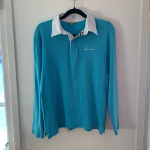 Burberry piké långärmad - Säljer denna sällsynta burberry pikén, storlek L men sitter som M. Ett väldigt litet hål (se tredje bild) som inte märks vid användning annars superbra skick. Självklart äkta. Skriv om  du har några frågor eller vill ha mer bilder