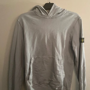 Stone island hoodie - En sparsamt använd Stone island hoddie i färgen grå/blå. Storleken är 170/14 år.  inköpt på NK i Stockholm så givetvis äkta. 