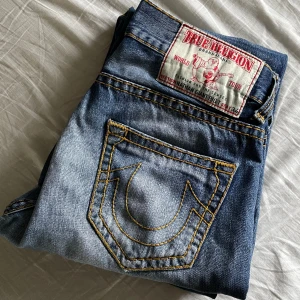 True Religion Jeans - Modellen Nathan Giant Big T Storlek 33 clean wash loose fit, lite heeldrag