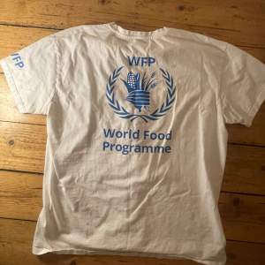 Helt ny vit World Food Programme t-Shirt. En fet T-shirt denna, med bild i rygg och text på armen. WFP är en bransch i FN och i nuläget hjälper det Palestinska folket mest av alla organisationer i Gaza. De tar in lastbilar fulla med mat som delas ut.