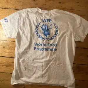 Helt ny vit World Food Programme t-Shirt. En fet T-shirt denna, med bild i rygg och text på armen. WFP är en bransch i FN och i nuläget hjälper det Palestinska folket mest av alla organisationer i Gaza. De tar in lastbilar fulla med mat som delas ut.