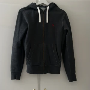 Polo Ralph Lauren tröja - Superfin zip-up hoodie från Polo Ralph Lauren i en mörkgrå färg med rött märke. Storleken är Xs men passar även S. Nypris 2100, Mitt pris 449 men kan såklart diskuteras!❤️