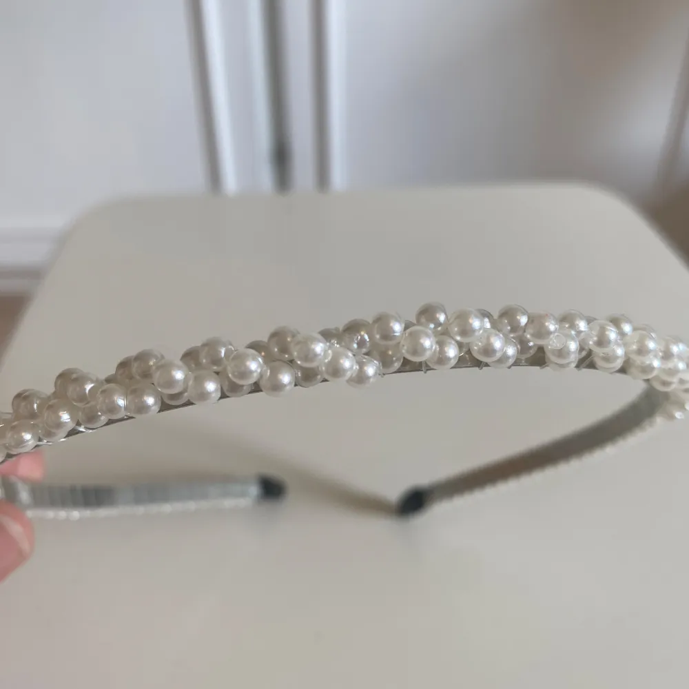 Ett elegant diadem dekorerat med vita pärlor. Diademet har en smal form och är perfekt för att ge en sofistikerad touch till din frisyr!. Accessoarer.