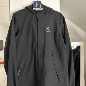 Haglöfs jacka  - Jackan är i fint skick utöver att den har ett litet hål vid fickan som inte syns jätte mycket, storlek L passar även någon som har M eller XL  Fler bilder kan skickas vid intresse och kvitto finns även