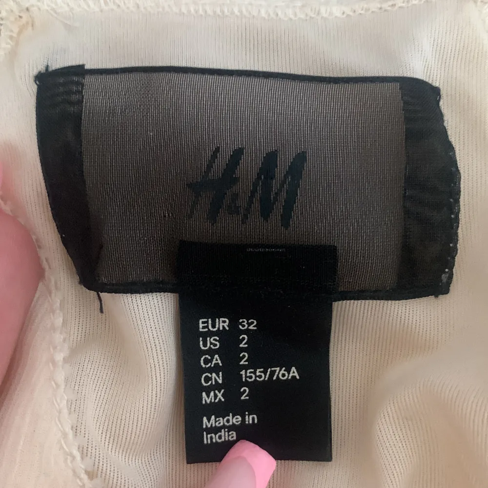 En beige topp från H&M dekorerad med silverfärgade paljetter i ett strålande mönster. Toppen har en halterneck-design och är ärmlös.. Yläosat.