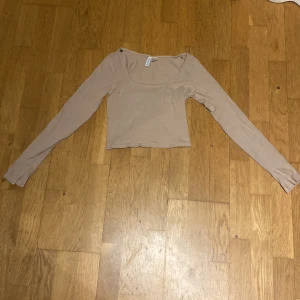 Beige långärmad tröja  - En urringad tröja som är lite öppen i armarna 