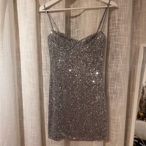 Paljettklänning - Silvrig, kort paljettklänning från zara. Storlek S men passar mig som normalt sett bär XS, den är däremot stretchig och har reglerade axelband. Oanvänd med prislappen kvar. Använd gärna köp nu-funktionen❤️
