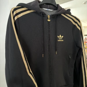 Adidas huvtröja - Snygg adidas tröja med dragkedja och luva. Kort modell. Storlek 38.