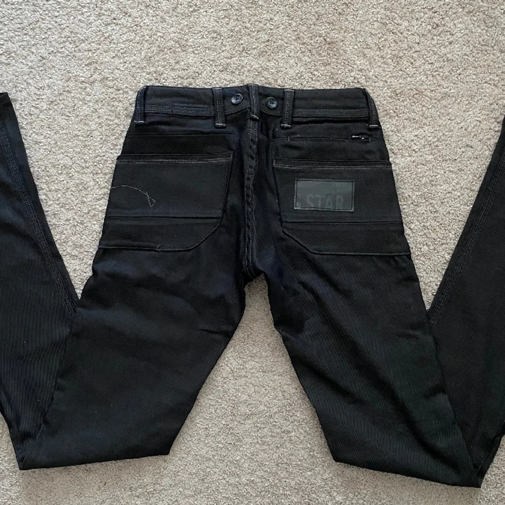 Ett par jättesnygga bootcut, g-star jeans köpta second hand som är i väldigt gott skick! Midjemåttet (tvärs över) är 36 cm och innerbenslängden är ungefär 76 cm. Färgen är egentligen mörkblå men ser mer svart ut. Skriv för fler frågor!. Jeans & Byxor.