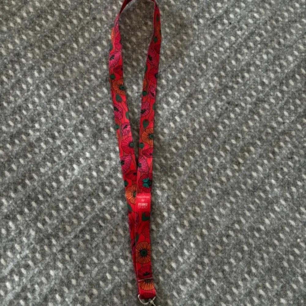 No more fear of losing your belongings! This colorful lanyard is ideal for both adults and children. It can also hold your badges or your cards. Designer: Pylones Studio Collection: Coquelicots. Accessoarer.