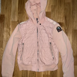 Parajumpers jacka dam XS - Säljer min rosa vår/sommar jacka ifrån PJ, med huva och blixtlås framtill. Jackan har två fickor på sidorna. Jackan har även en logga på vänster ärm.  Sparsamt använd, hel och ren.   Inköpt ifrån Johnells.  Nypris 2.499kr kvitto finns.