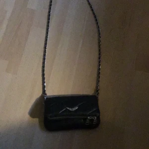 Zadig Voltaire väska - Säljer min jättefina Zadig väska. Skicket är helt ok men har lite slitage. En av kedjorna (bild 2) har lossnat men går nog lätt att ta bort eller laga, därför är priset lågt. Kan mötas upp i nacka eller Sthlm. Kan möjligtvis pruta❤️❤️