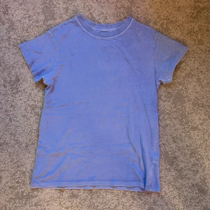 Blå t-shirt - Blå t-shirt från Pull&Bear. Tröjan har en urtvättad look, väldigt skön och passar perfekt för en mer slapp känsla. Använd en del men är i bra skick.  Måtten är från halsen till nedersta kanten 60cm, 50cm bred och från ärm till ärm 60cm 