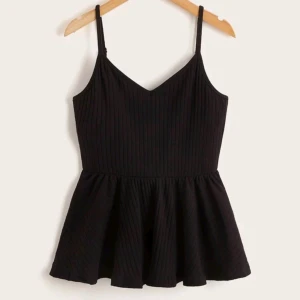 Svart volangtröja - Säljer ett snyggt svart linne med peplum. Den är ribbad och har smala axelband. Perfekt för både vardag och fest!💕