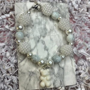 Vit armband med silvrig kedja  - Vit armband med silvrig kedja som går att justera, armbandet har även en vit berlock. 