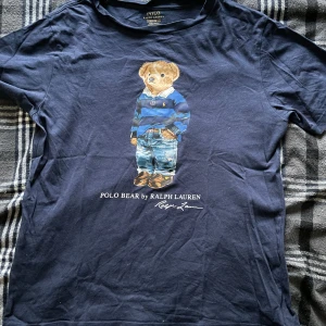 Ralph Lauren Polo Bear T-Shirt - En fin T-Shirt av ralph lauren i polo bear trycket. Väldigt skön att ha på sig och den e fin. Skick 9/10. Använde den mycket förr nu är den bara i garderoben och tar plats så valde att sälja den. Pris går att diskutera. 