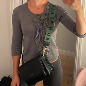 Axelremsväska  - Axelremsväska med totalt 6 fack. Svart och mörkgrön med guldiga deltaljer.