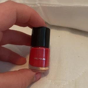 Rött nagellack - Ett rött nagellack med svart lock. Färgen är intensiv och passar för en elegant manikyr.