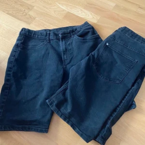 Svarta jeansshorts - Ett par svarta jeansshorts med fickor fram och bak. Shortsen har en klassisk design med knapp och dragkedja framtill.