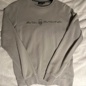 Tröja - Grå Sail racing tjocktröja i nyskick. Använd ett fåtal gånger men de är inget som syns. Tröjan är i storlek S men tror nog att även passar på M.