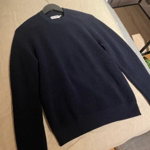 Stickad tröja  - Riktigt fet stickad East West tröja i storlek S. Tröjan är marinblå och är nästintill i nyskick, bara använd 1-2 gånger. Ordinarie pris 700kr