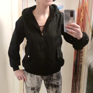 Oanvänd ny jacka vändbar - Svart, skön, vändbar jacka med hoodie. Endast provad. Står M i den men snarare S. Funkar nog även XS för mer baggy fit.  För referens: Jag är 169cm. Vanligtvis stl S.  Barnet på bild 3 är 143 cm.  Nypris 400. 
