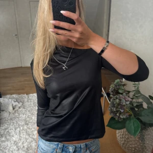 Festtopp  - Snygg festtopp med asymmetrisk urringning, skimrigt svart material