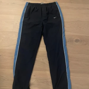 Vintage Nike träningsbyxor/trackpants - Vintage Nike trackpants som sitter perfekt loose/baggy på mig som är cirka 175🔥🔥🔥Dom är i storlek 164-176 Dom är i bra skick förutom att dom är lite trasiga där man drar åt snöret men funkar perfekt ändå👍👍👍