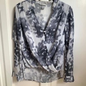 Mönstrad blus - H&M - Grå/blå mönstrad omlottblus från H&M. Storlek 36, men passar även en 34. I fint skick 🌸
