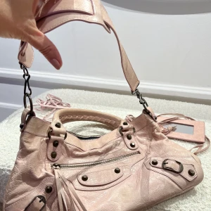Balenciaga city ljusrosa - Vintage och med en fläck fram men annars bra skick. Spegel axelrem och extra snören finns! Super söt färg till vår och sommar 