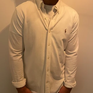 Ralph Lauren skjorta  - Denna tunna knit oxford polo skjorta är perfekt till en varm sommardag. Den är oanvänd och är i storlek L men sitter som M. Nypris på denna är ca 2000kr. Har du några frågor är det bara att skriva