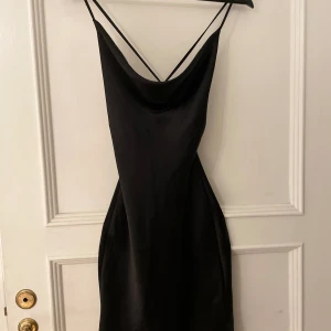 Festklänning 🎉 - Figursydd, kort, satin klänning i storlek 32. Snörad i ryggen!🤩Säljer för att jag har växt ur den. Sömmen har dock spruckit lite på vänster sida och tyvärr gjort ett litet hål (som garanterat kan fixas!!) ..🌺