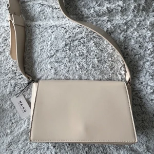 Väska  - Beige väska från NA-KD. Helt ny aldrig använt, prislappen kvar. En rymlig väska men många bra fack. 