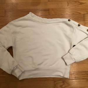 Jättefin kort vit tröja med knappar på ena ärmen. Den är typ som en hoodie utan luva. Säljer eftersom den inte passar mig. Sparsamt använd.