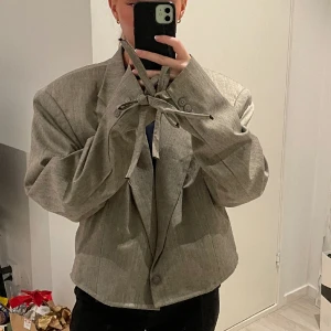 Kavaj - Säljer denna kavajen i lite kortare modell med detaljer på armarna. Oversized fit, passar en S/M.  Grå/beige färg. 