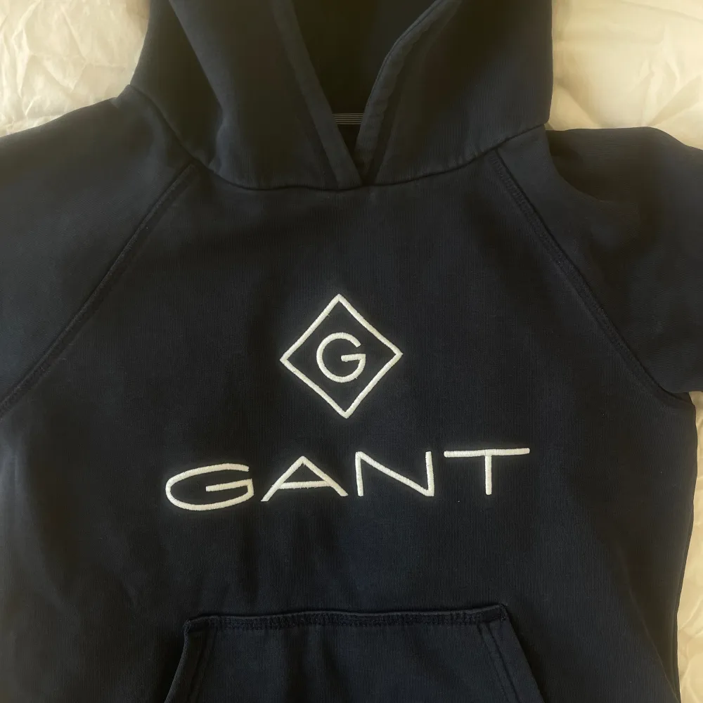Säljer denna hoodie från Gant i barnstorleken 146/152 i en marinblå färg. Den har använts ett fåtal gånger och är fortfarande i superbra skick!🫶🏽. Hoodies.