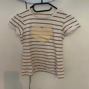 Vit och brun liten tröja  - För lite mindre barn, ett ljus brunt hjärta i mitten, den har ett fläck bredvid hjärtat 