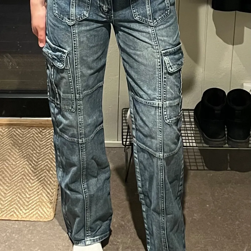 Lite mörkblåare cargo-jeans i storlek 36. Modellen är straight och de är mid-waist, samt med lite fickor och sömmar som detaljer.  Sparsamt använda och säljer då de är lite små och aldrig används.. Jeans & Byxor.