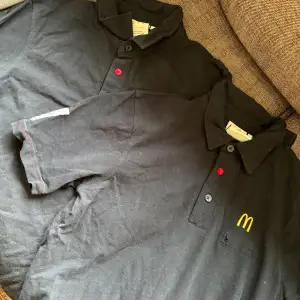 Två styckena svarta piké med McDonalds motiv på i storlek XS. 