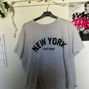 Grå kortare T-shirt med text ”NEW YORK” - Hej! Jag säljer min ljusgråa T-shirt med texten ”New York” i svart pga att den är för kort för mig🩶