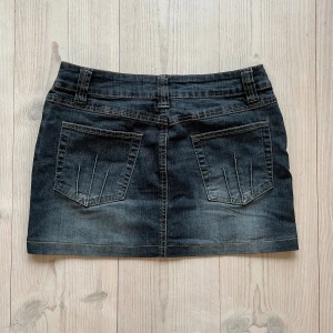 Lågmidjad jeanskjol  - Mörkblå/grå lågmidjad jeanskjol från KappAhl i storlek 36 som jag har sytt upp från en längre kjol. Tvärs över midjan är det 37 cm + stretch och längs med sidan är det 32 cm. Fint skick. Kom privat för bilder på sömmen. Använd gärna köp nu!